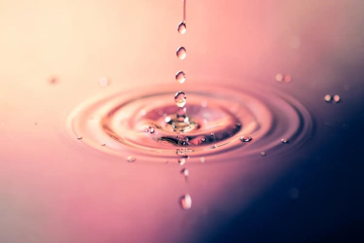 Close-up de gotas de água caindo sobre uma superfície, simbolizando infecção ou inflamação.