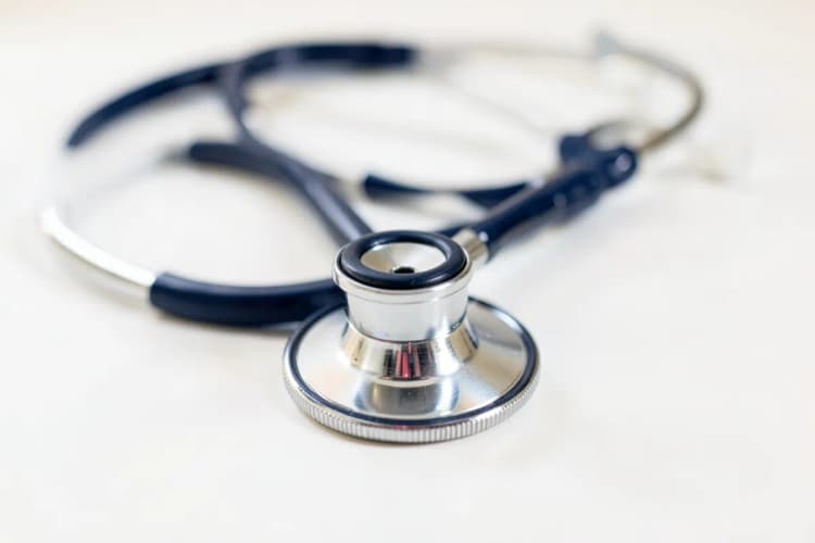 Imagem de um estetoscópio sobre um fundo branco, simbolizando diagnóstico médico.