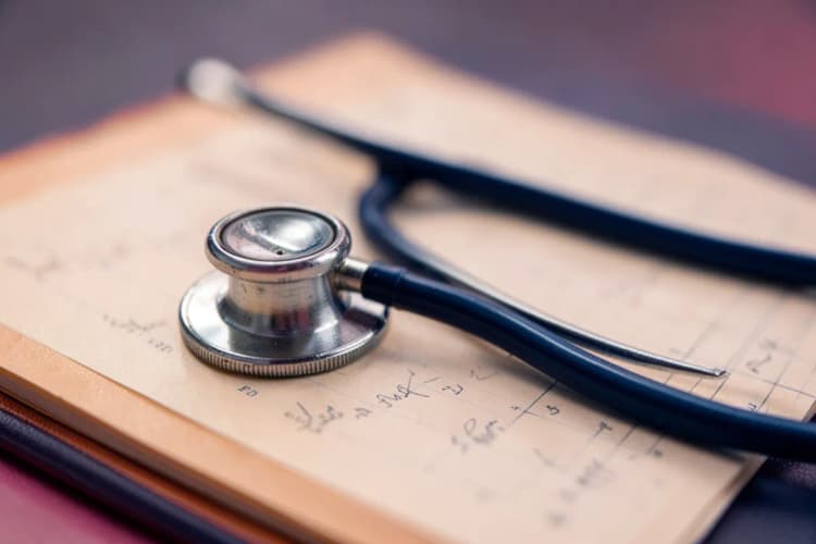 Um close-up de um estetoscópio sobre um prontuário médico.